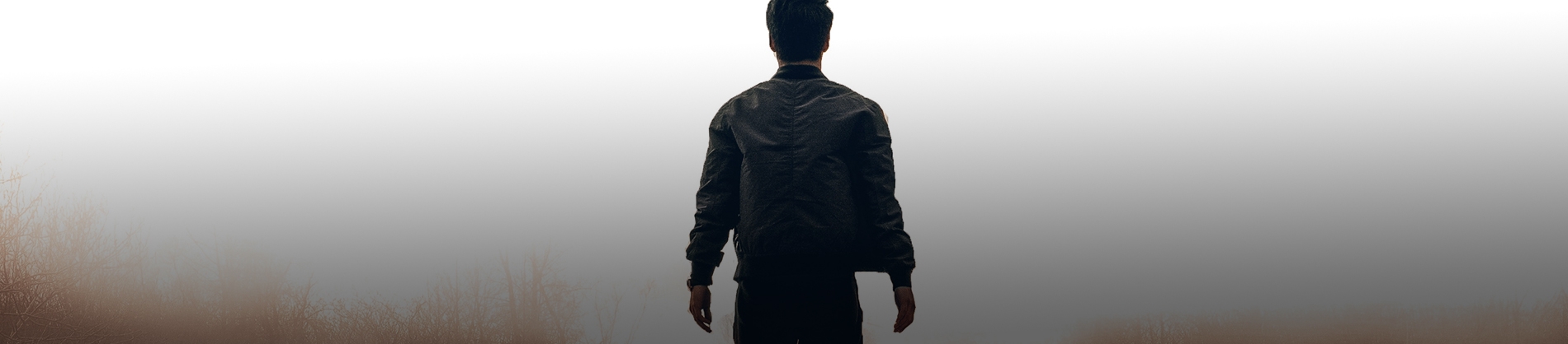 A man stood in a field looking towards fog A man stood in a field looking towards fog