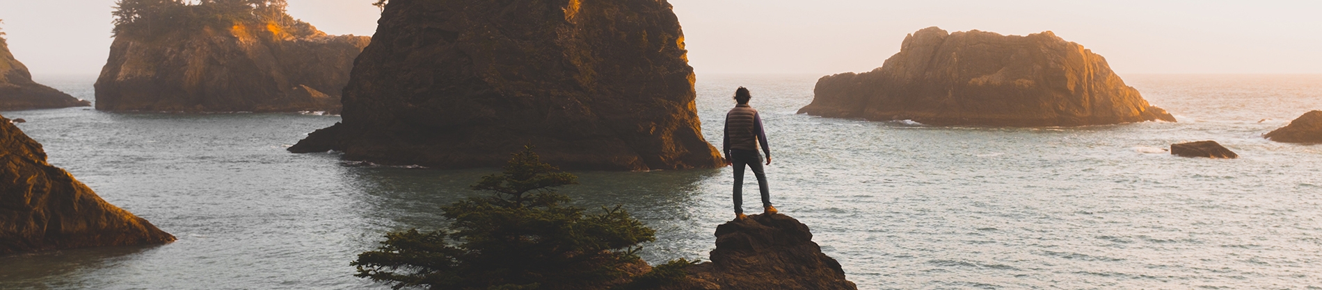 A man stood on a rock overlooking the ocean A man stood on a rock overlooking the ocean