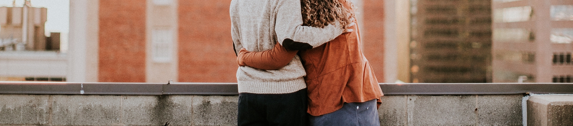 A man and women hugging, while looking across a skyline A man and women hugging, while looking across a skyline
