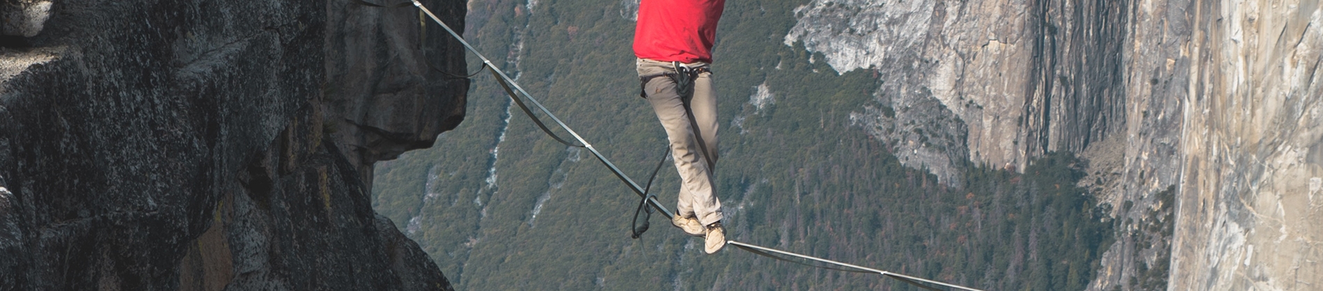 A man walking on a tightrope across a valley A man walking on a tightrope across a valley