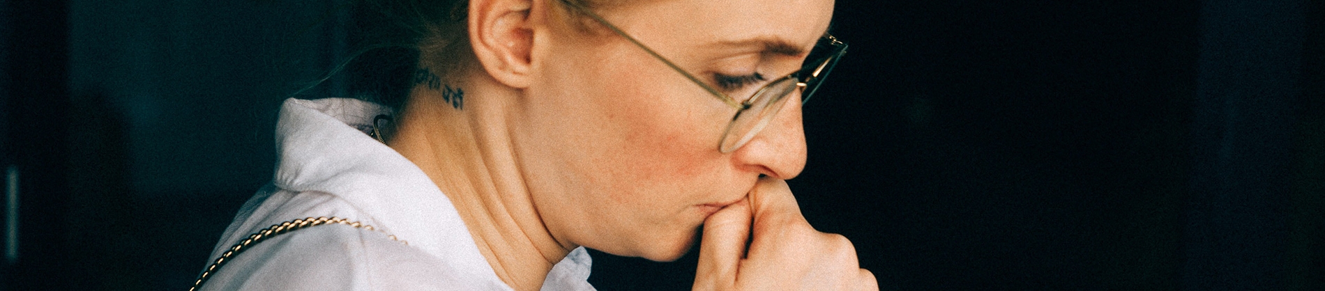 A women looking nervous with her lips against her thumb A women looking nervous with her lips against her thumb