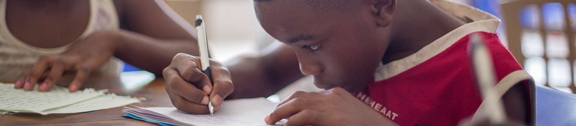 A child sat at a table writing A child sat at a table writing