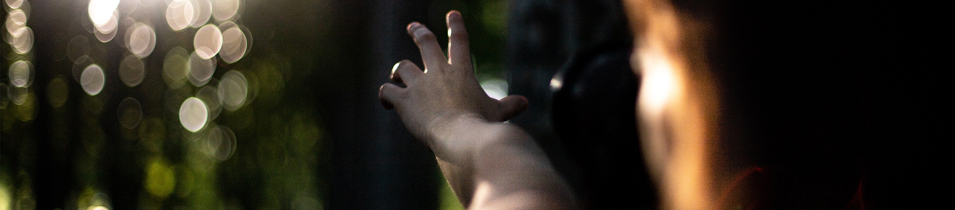 A person reaching their hand forward towards the sun A person reaching their hand forward towards the sun