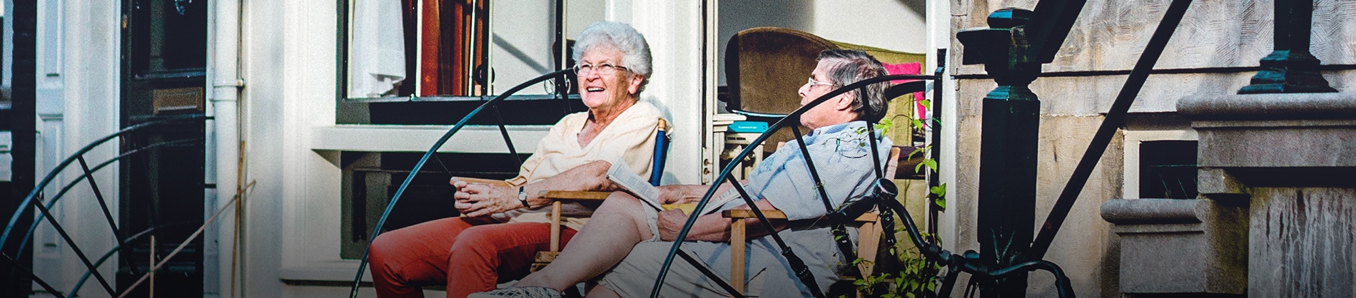 An elderly couple sat on chairs outside their home An elderly couple sat on chairs outside their home