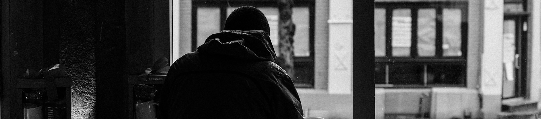 A black and white photo of a man walking through a town A black and white photo of a man walking through a town
