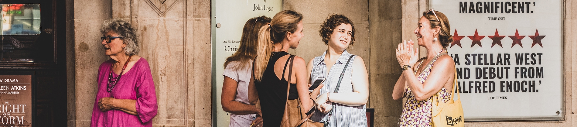 A group of women talking outside of a theatre A group of women talking outside of a theatre