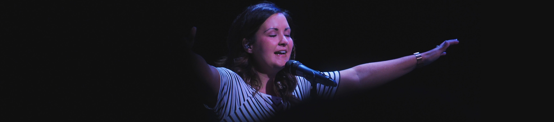 A woman leading worship with a spotlight on her A woman leading worship with a spotlight on her