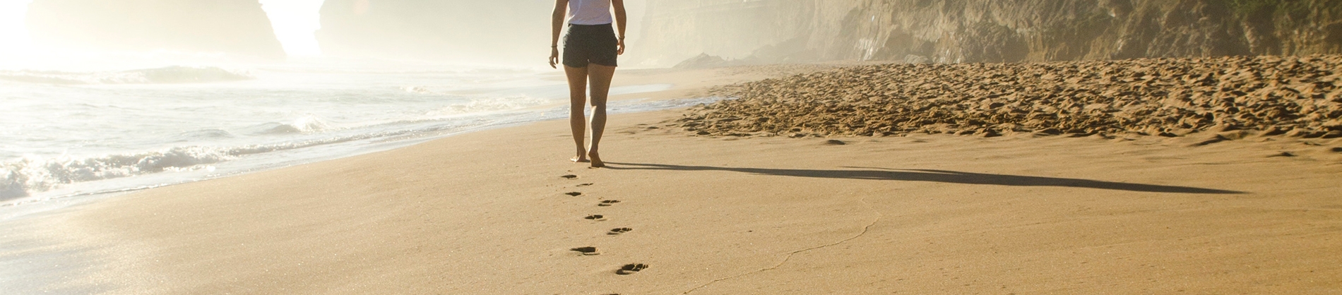 A women walking along the beach leaving footprints in the sand A women walking along the beach leaving footprints in the sand