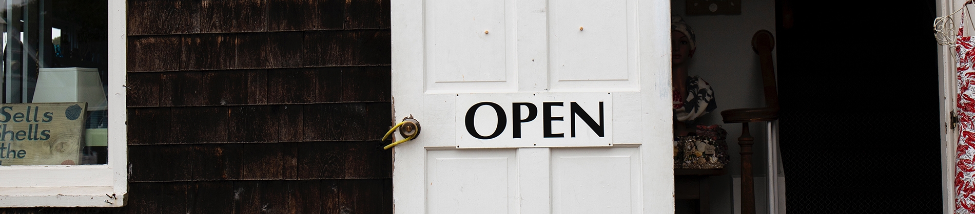 A shop with a white door with a painted 'Open" sign on it A shop with a white door with a painted 'Open" sign on it