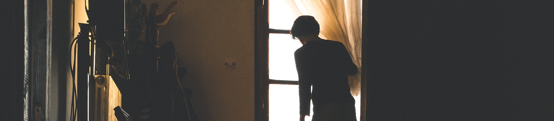 A man opening the curtain to look out of a window A man opening the curtain to look out of a window