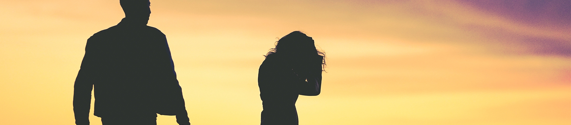 Silhouettes of a women with her head in her hands and a man walking towards her Silhouettes of a women with her head in her hands and a man walking towards her