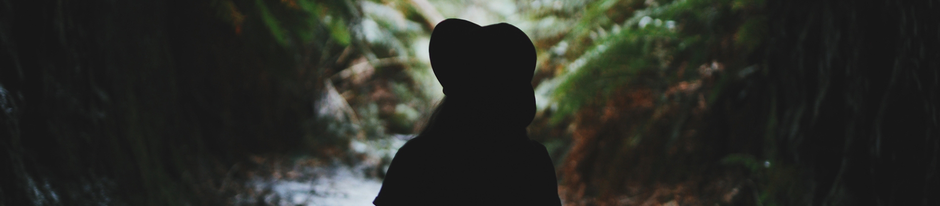 A women with a hat walking through a forest path