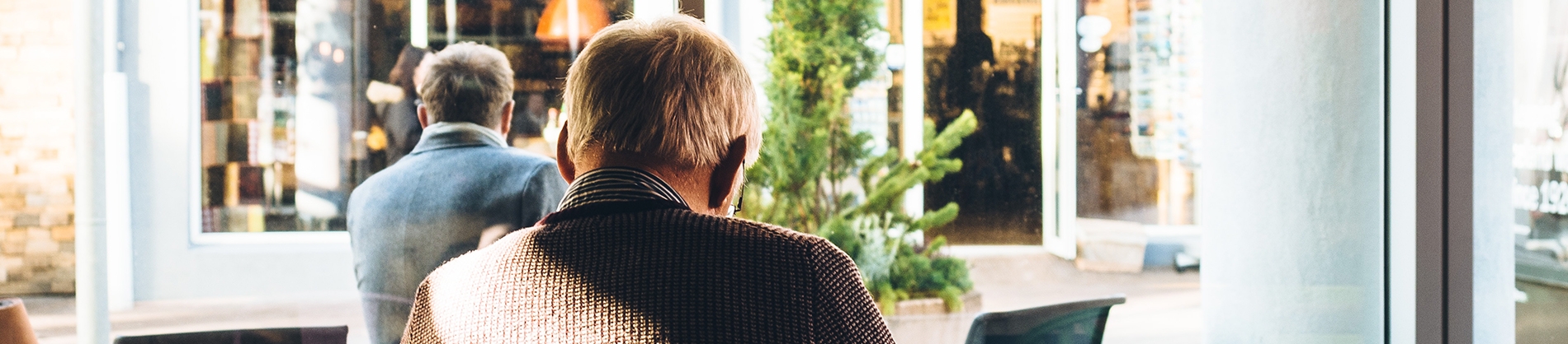A elderly man sitting at a cafe table A elderly man sitting at a cafe table