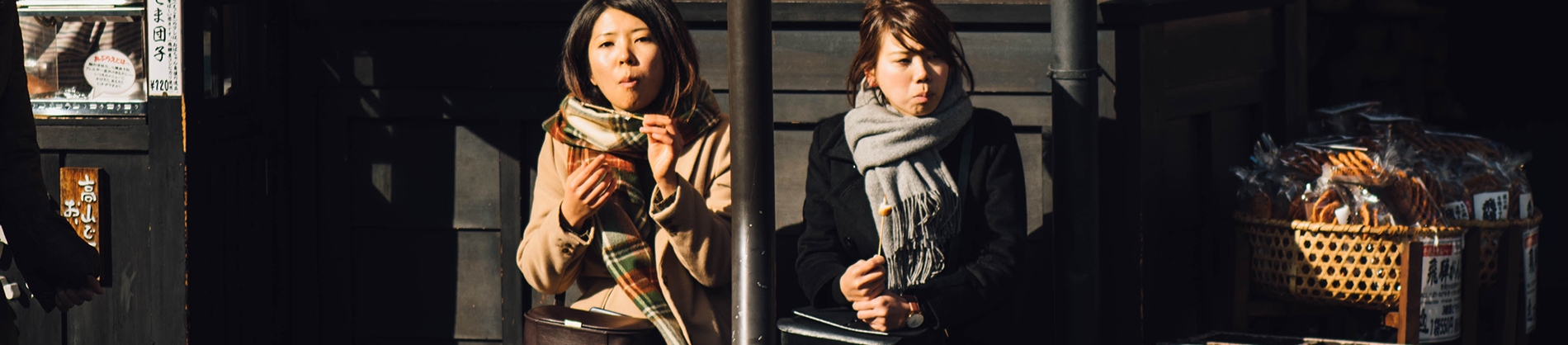Two women sat on a bench eating Two women sat on a bench eating