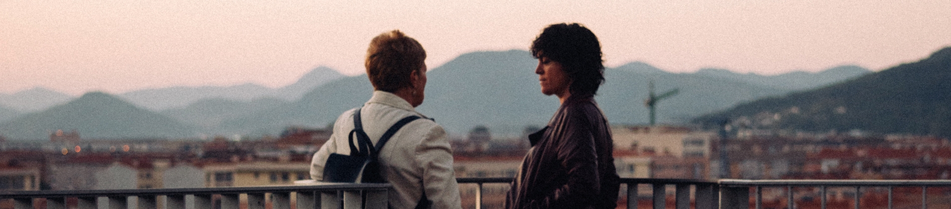 Two women stood on a balcony talking Two women stood on a balcony talking