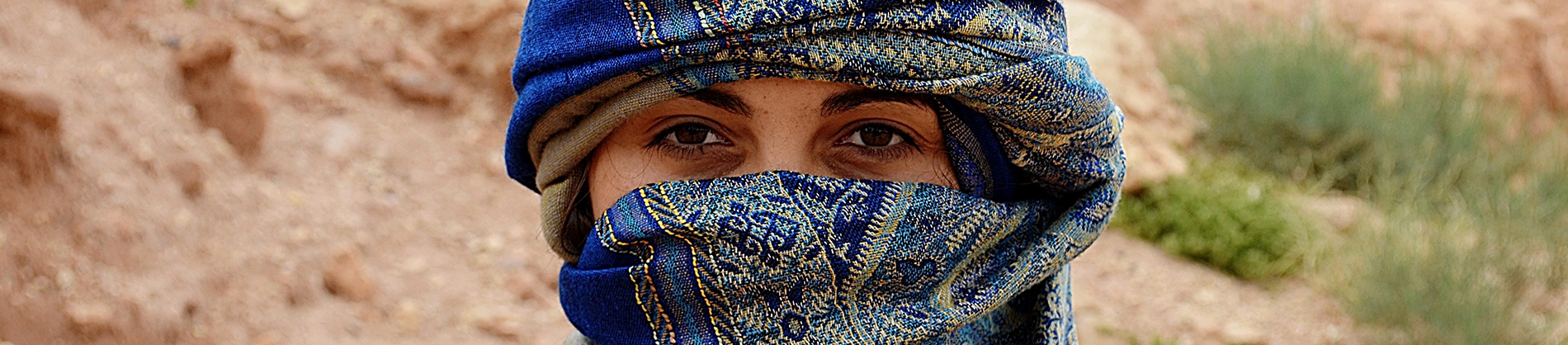A women wearing a blue head scarf stood in the desert