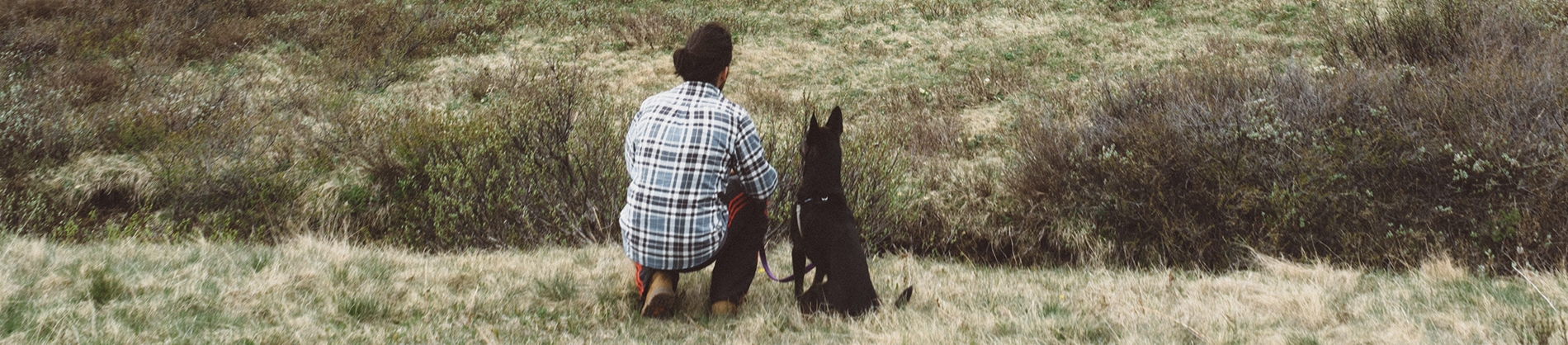 A man and his dog kneeling in a field