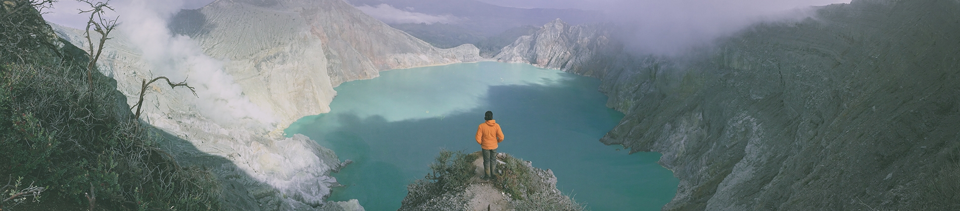 A man looking over a cliff edge into a valley A man looking over a cliff edge into a valley