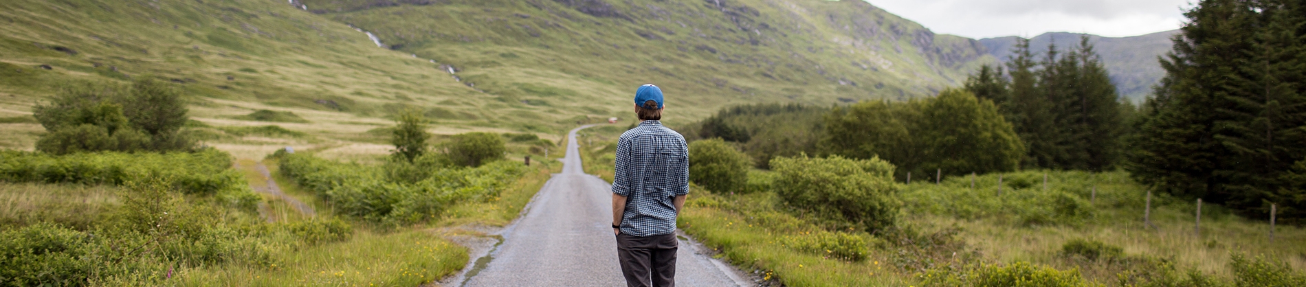 A man looking back on a long path in a valley A man looking back on a long path in a valley