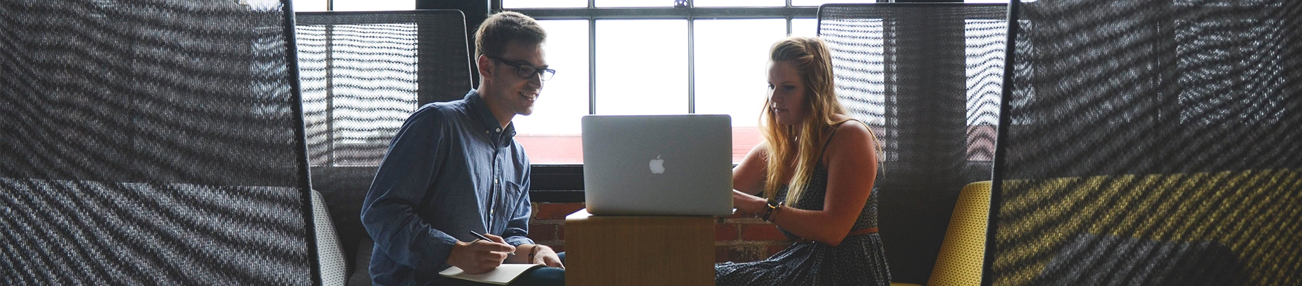 Two work colleagues sat in a booth on a laptop Two work colleagues sat in a booth on a laptop