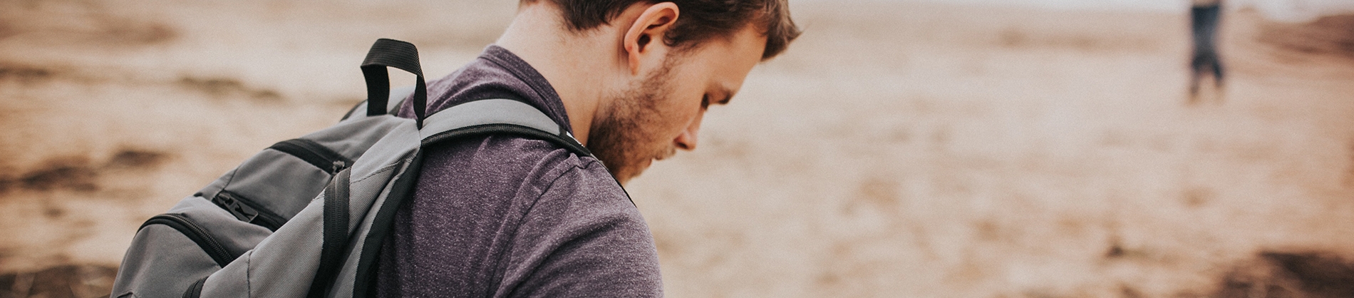 A man looking down, walking across a beach A man looking down, walking across a beach