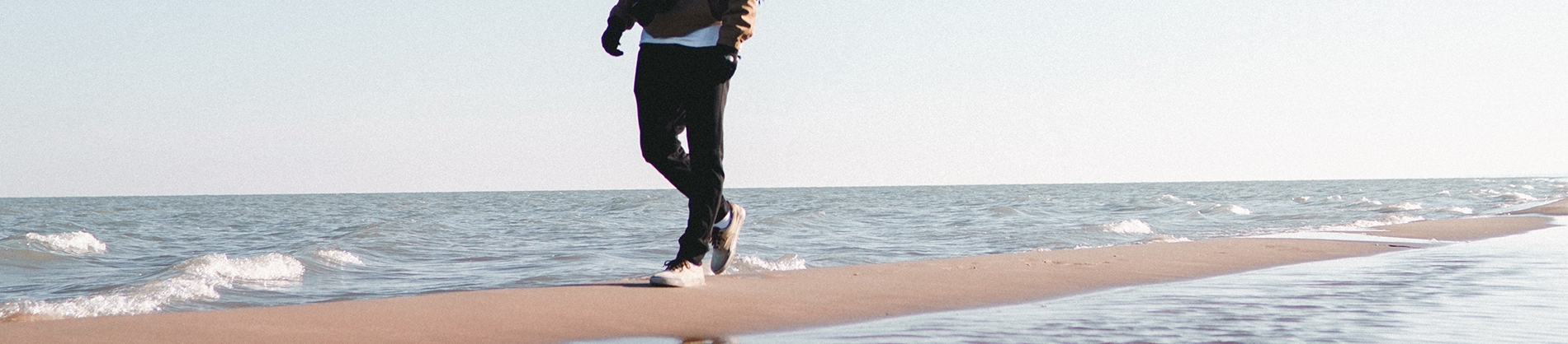 A guy walking along the sand next to the ocean A guy walking along the sand next to the ocean