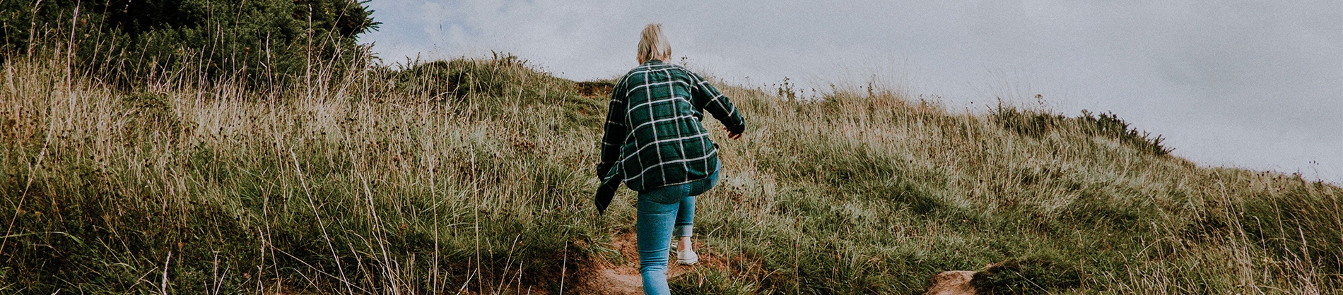 A women climbing up a grassy hill A women climbing up a grassy hill