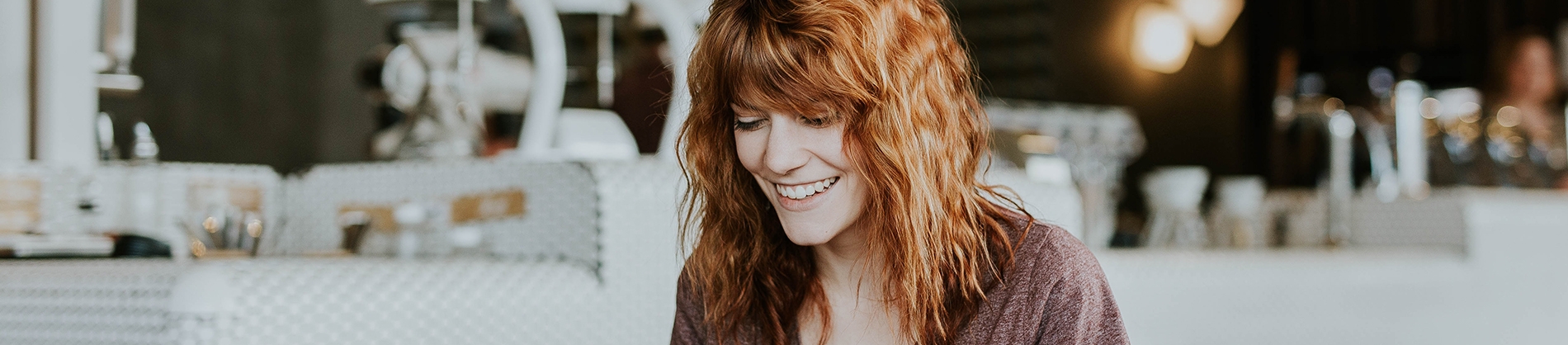 A women sat at a table looking down smiling A women sat at a table looking down smiling