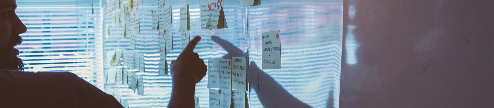 A man pointing at post-it notes on a whiteboard A man pointing at post-it notes on a whiteboard