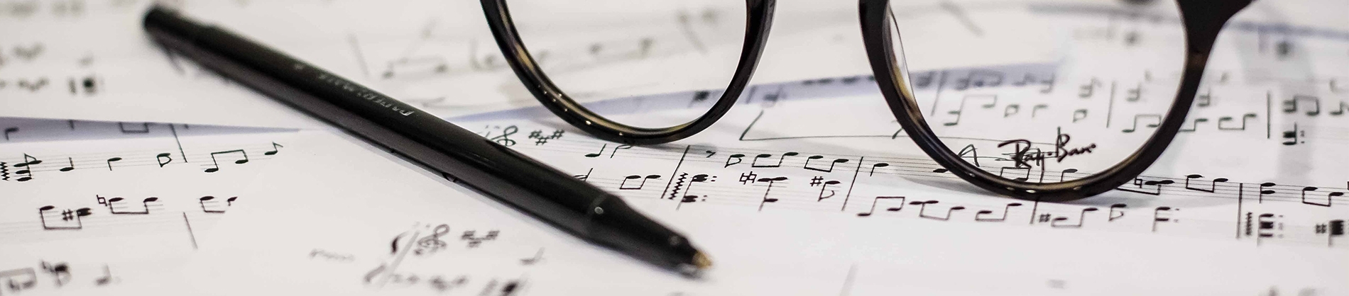 Sheet music with a pair of glasses and pen resting on top