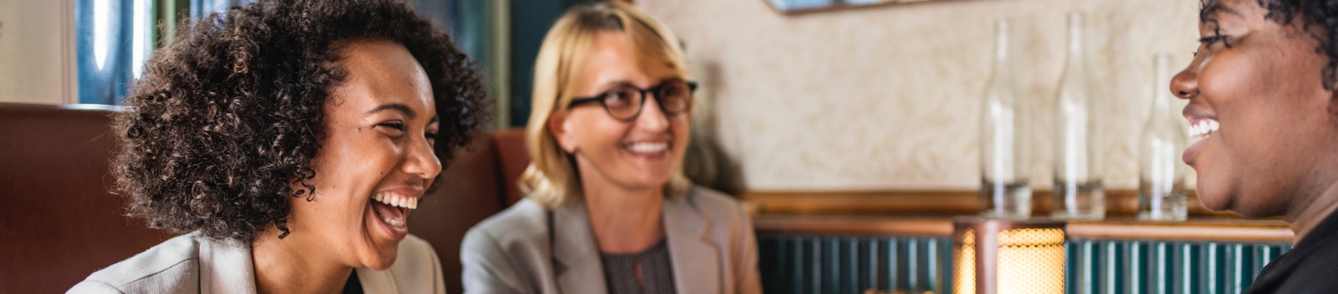 Three women chatting and laughing together at a meeting table Three women chatting and laughing together at a meeting table
