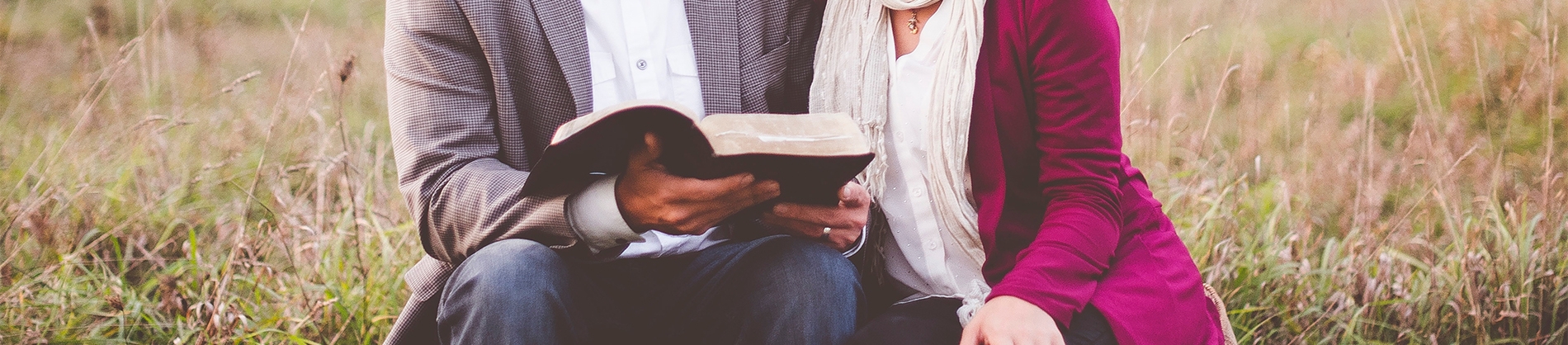 A married coup sat together in a field reading a bible A married coup sat together in a field reading a bible