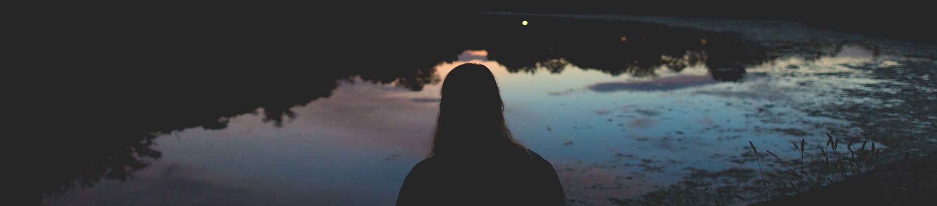 A silhouette of a women looking over a river at sunrise A silhouette of a women looking over a river at sunrise
