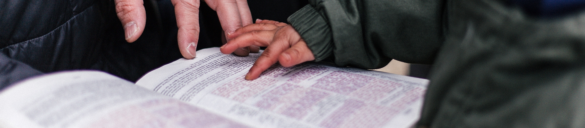 A child pointing at a bible verse with their father A child pointing at a bible verse with their father