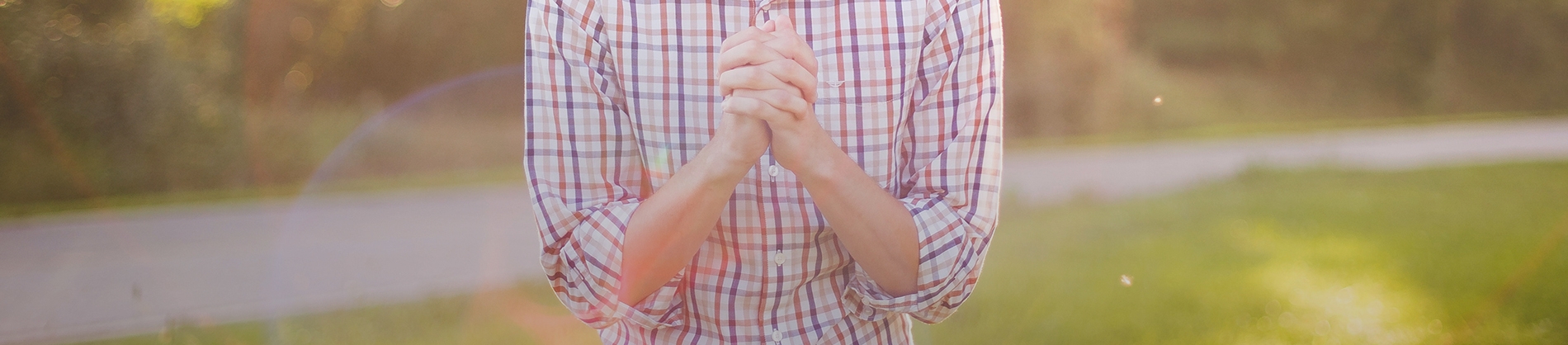 A man stood in a garden with his hands together in prayer A man stood in a garden with his hands together in prayer