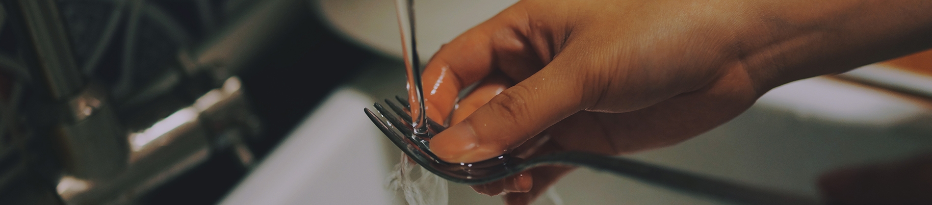 Someone washing up a fork in the sink