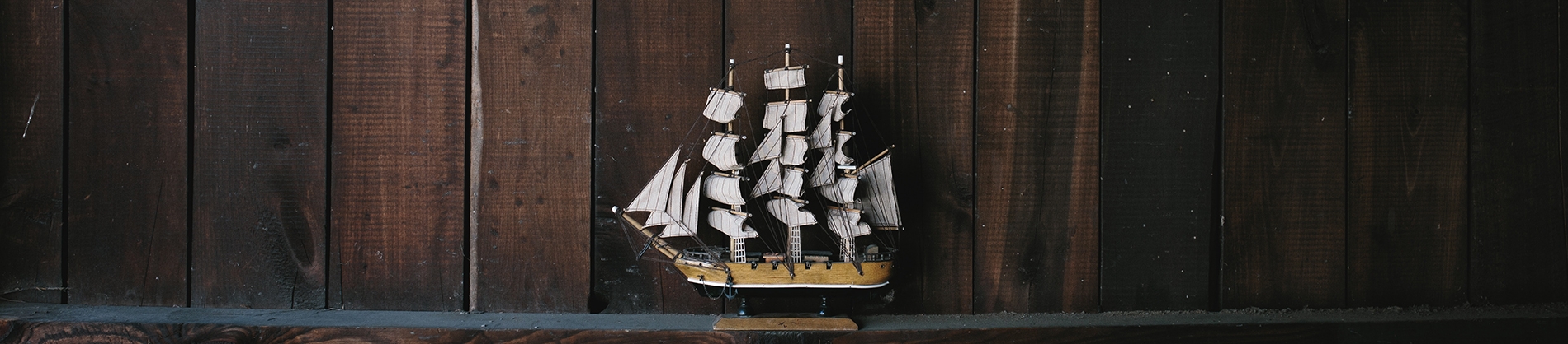 A replica of a ship with a wooden wall behind A replica of a ship with a wooden wall behind