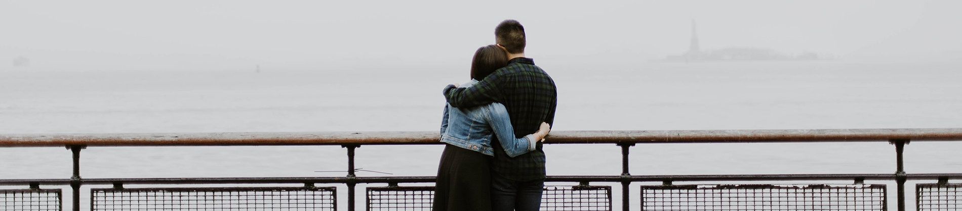 A couple hugging while looking out over railings to the sea A couple hugging while looking out over railings to the sea