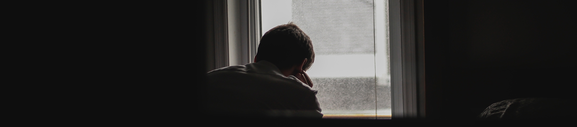 A man sat at a window resting his head on his hands