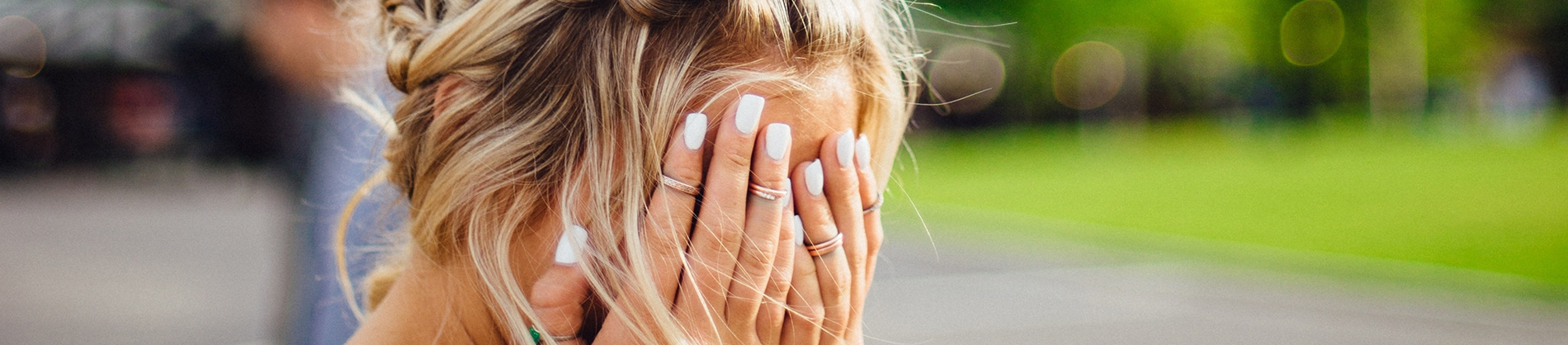 A women with her hands over her face with a blurred background A women with her hands over her face with a blurred background