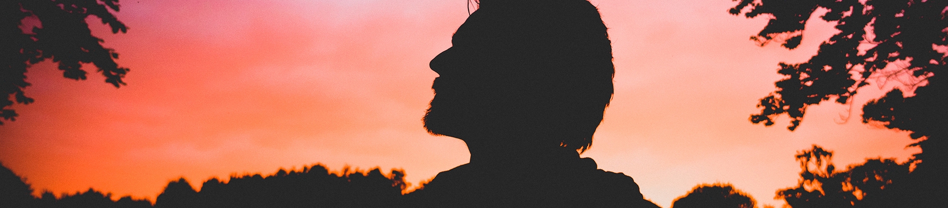 A silhouette of a man looking up with the sunrise behind him A silhouette of a man looking up with the sunrise behind him