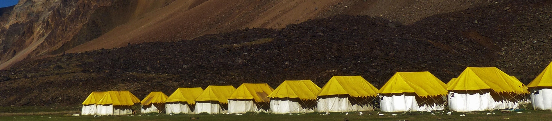 White and Yellow tents lined up on a mountain side White and Yellow tents lined up on a mountain side