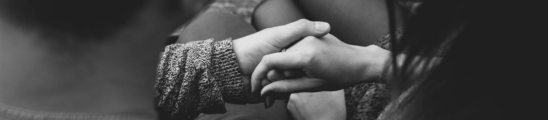 Two people holding hands praying