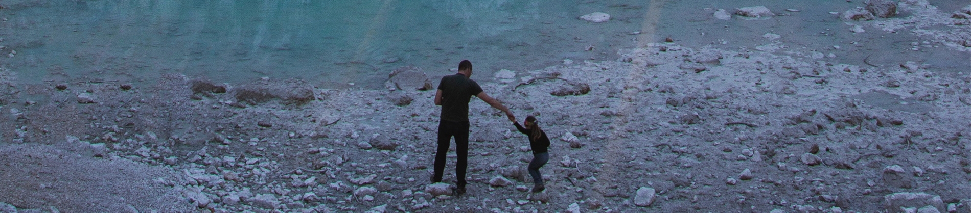 A father and son on the beach. The child is holding the fathers hand and jumping over rocks A father and son on the beach. The child is holding the fathers hand and jumping over rocks