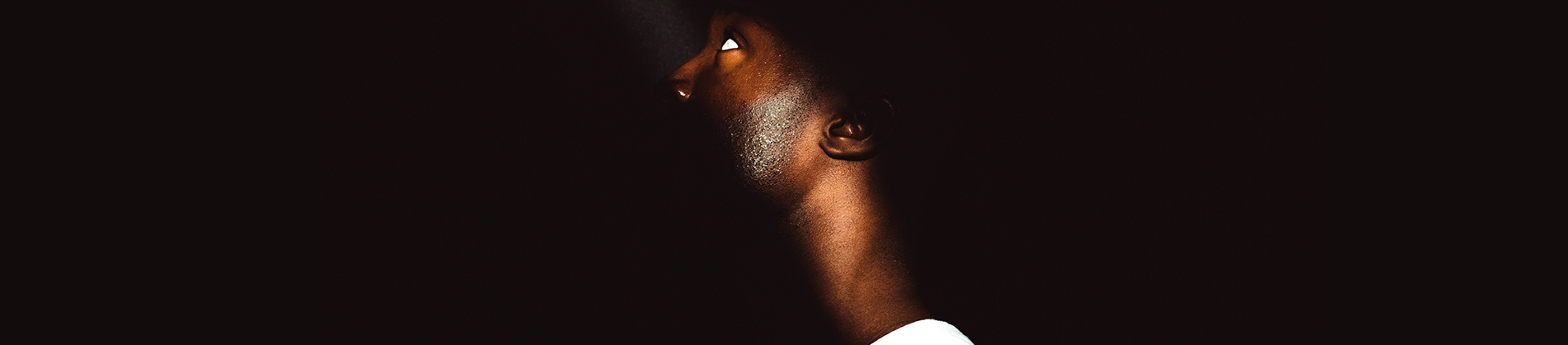 A man looking up to a ray of sunlight on his face A man looking up to a ray of sunlight on his face