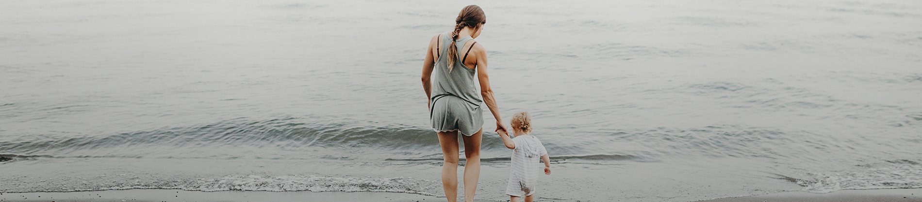 A women holding her child's hand going into the sea A women holding her child's hand going into the sea