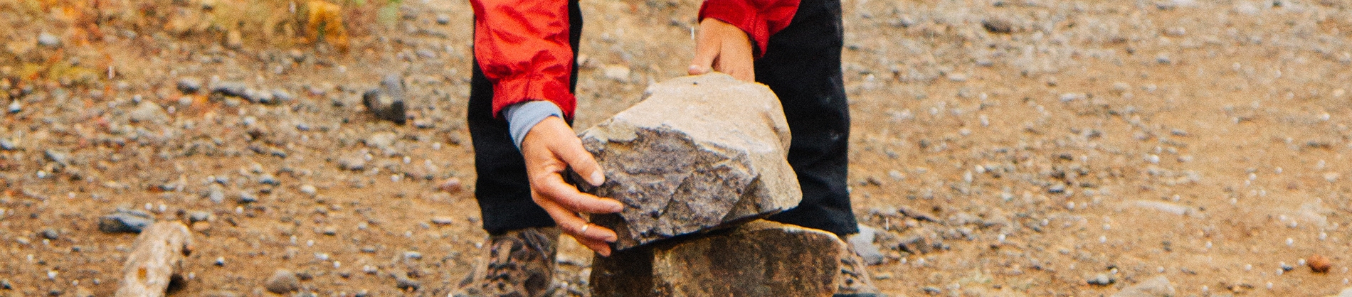 A person picking up a large rock A person picking up a large rock