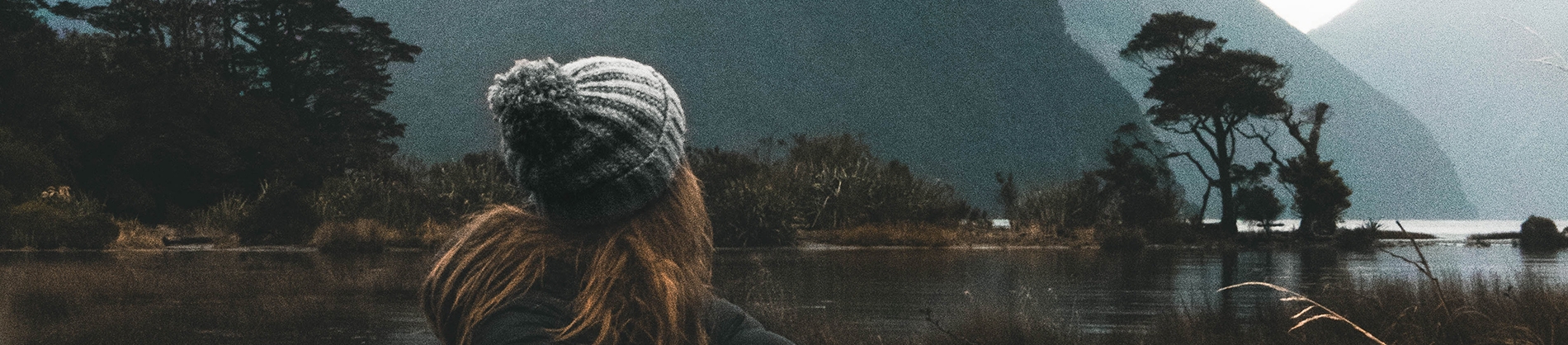 A women in a wooly hat looking out over a lake and mountains A women in a wooly hat looking out over a lake and mountains