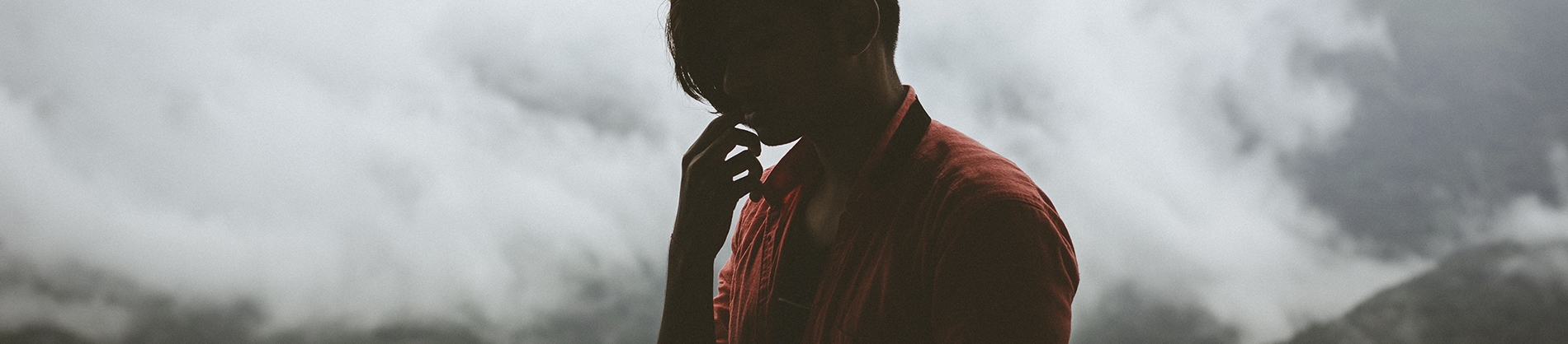 A thinking man stood with a cloudy mountain range behind him A thinking man stood with a cloudy mountain range behind him