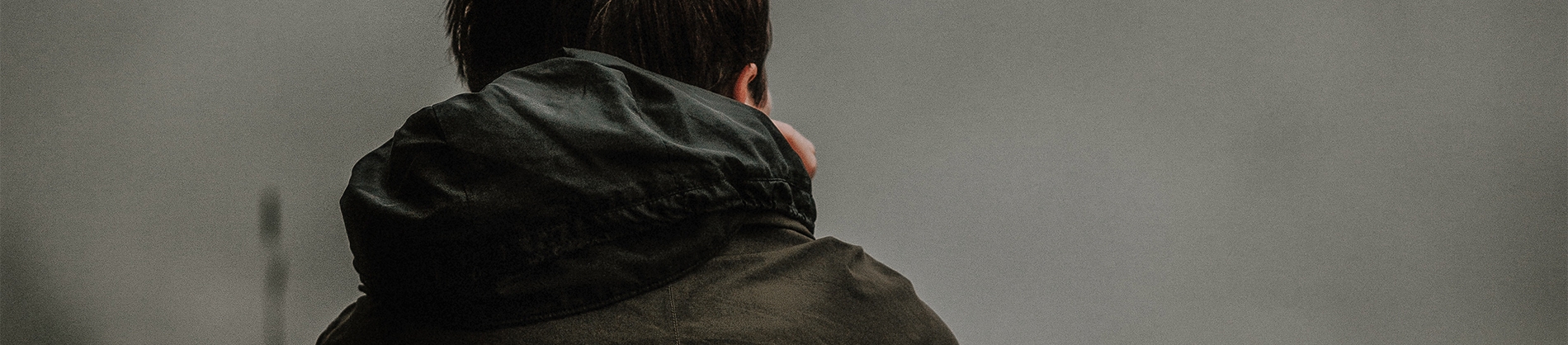 A man in a black raincoat facing away A man in a black raincoat facing away